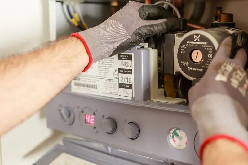 Hands adjusting pipes and equipment during plumbing maintenance